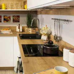 Nowoczesna kuchnia z drewnianym blatem, czarnym zlewem i płytą indukcyjną.